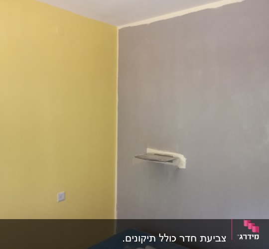 קיר צבוע בצהוב ואפור עם מדף קטן
